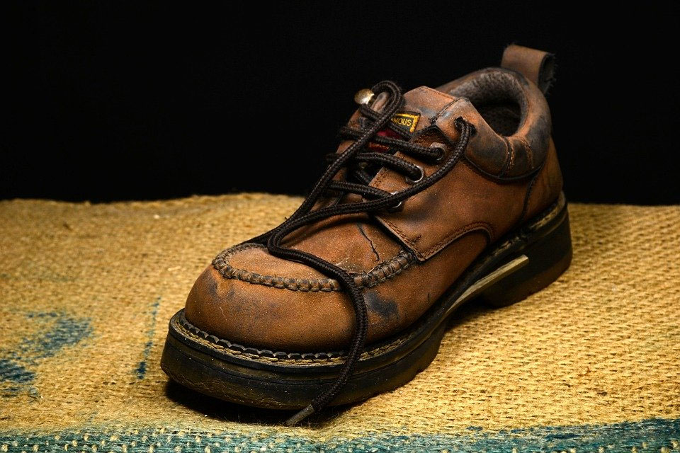 Zwei Personen binden gemeinsam mit einer Hand einen Schuh zu